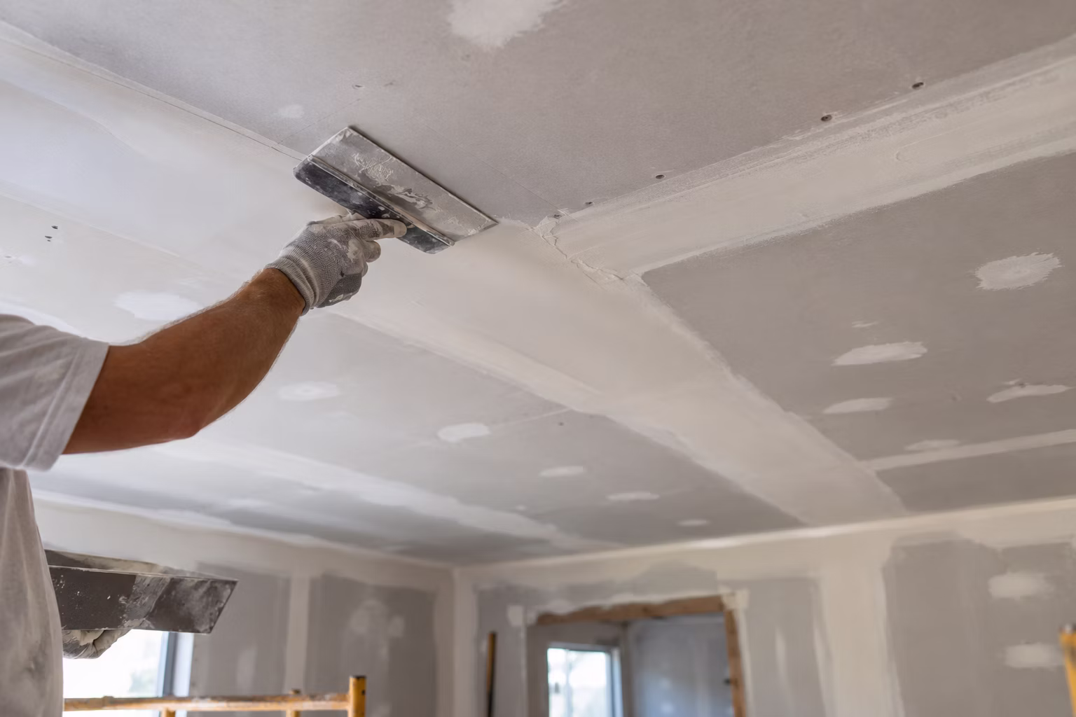 Drywall finisher smoothing joint compound on a ceiling in South Jersey
